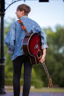 Woodbridge, Suffolk, İngiltere 13 Eylül 2020: 20 'li yaşlarda akustik gitarıyla rahatlayan ve poz veren bir kadın