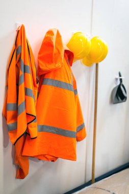 Yüksek görüş mesafesi olan koruyucu giysiler ve işçiler için kolay erişim için bir depoda asılı duran sert şapkalar. Depo, mağazalar, güvenlik teçhizatı