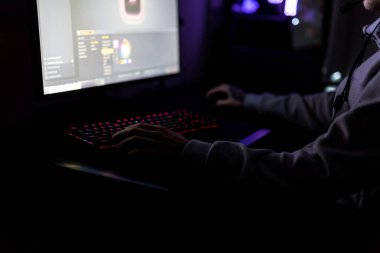 Profesyonel Oyuncu ya da Streamer, özel yapım bir oyun bilgisayarında birinci şahıs Shooter Online Video Oyunu oynuyor. O bir kulaklık takıyor ve bir klavye ve fare üzerinde çalıyor.