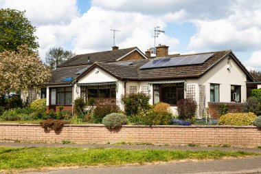 Woodbridge, Suffolk, İngiltere 30 Nisan 2021: Çatıda güneş panelleri olan küçük geleneksel bir bungalov. Yeşil enerji güneş enerjisi