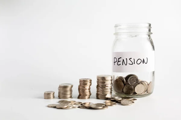 Coins stacked up next to an empty jar with a label on for pension fund. Pension, financial, savings, economy, investment concept