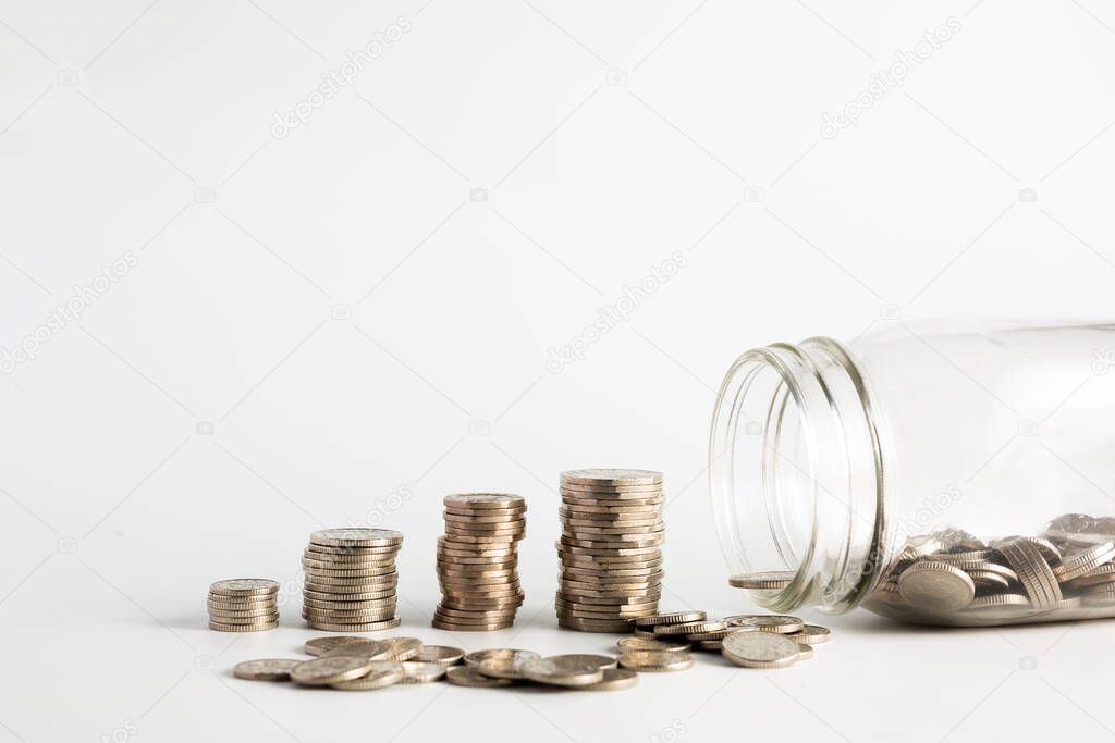 Coins stacked up next to a half empty jar with coins in and with a label on saying pension fund. Pension, financial, savings, economy, investment concept
