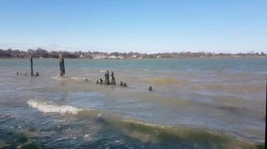 Güneşli bir bahar gününde, parlak mavi gökyüzü, Deben nehri ve Suffolk nehri ile eski ve harap bir ahşap yapının üzerinde dalgalar kırılıyor.