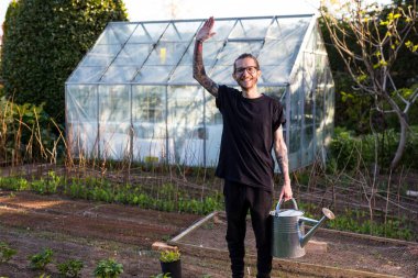 Woodbridge Suffolk UK Mayıs 08 2020: Sebze bahçesinde gururla çalışan genç erkek dövmeli bir hippi organik sebze yetiştiriyor