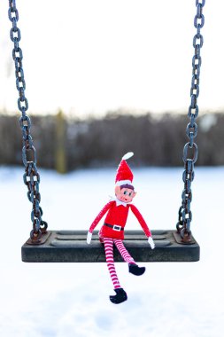 Woodbridge Suffolk UK 11 Şubat 2021: Halka açık bir parkta salıncakta oynayan yaramaz bir Noel elfi. Yaramaz, noel, yaramaz elf konsepti