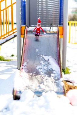 Woodbridge Suffolk UK 11 Şubat 2021: Halka açık bir parkta kayan bir çocuk üzerinde oynayan yaramaz bir Noel elfi. Yaramaz, noel, yaramaz elf konsepti