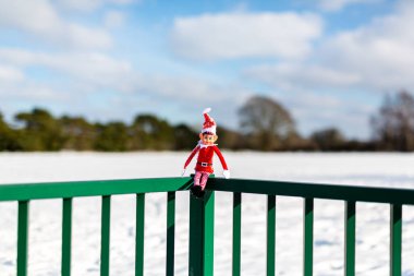 Woodbridge Suffolk İngiltere 11 Şubat 2021: Yaramaz bir Noel elfi dışarıda karlı kış manzarasında kış güneşinin tadını çıkarıyor. Yaramaz, noel, yaramaz elf konsepti