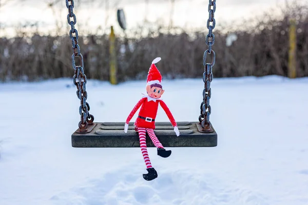Woodbridge Suffolk UK 11 Şubat 2021: Halka açık bir parkta salıncakta oynayan yaramaz bir Noel elfi. Yaramaz, noel, yaramaz elf konsepti
