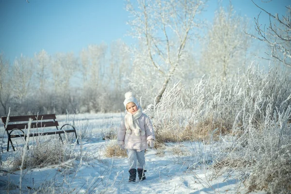 一个戴着温暖的白色帽子和围巾的孩子，在冬天的森林里散步，飘雪，冬天的魔法，灿烂的感情，保护着皮肤免受霜冻 — 图库照片