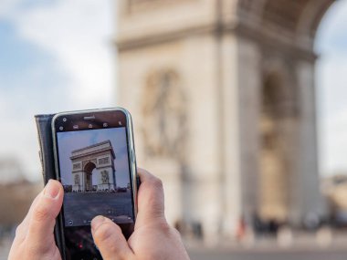 Bir turist Paris 'te Zafer Takı' nın cep telefonuyla fotoğrafını çekiyor.