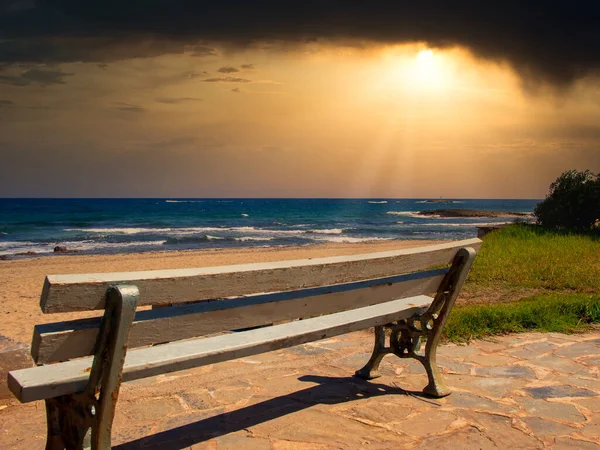 stock image A lonely bench by the sea at sunset - loneliness