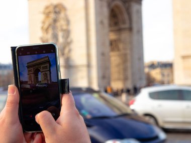 Bir turist Paris 'te Zafer Takı' nın cep telefonuyla fotoğrafını çekiyor.