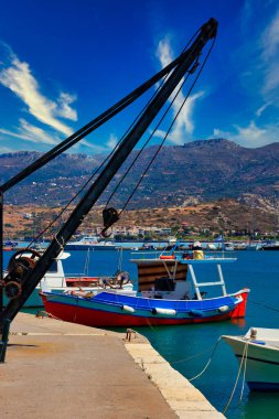 Sitia limanında eski bir vincin arkasında balıkçı gemisi var.