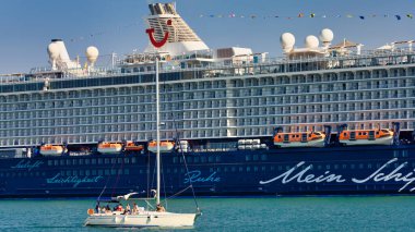 Heraklion Limanı 'ndaki TUI Gemi Şirketi' nden Mein Schiff 5 yolcu gemisinin önünde bir yelkenli gemisi.