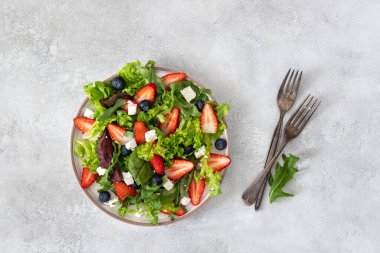 Taze çilek, roka soslu yabanmersini salatası, peynir, zeytinyağı, bitkiler. Sağlıklı yemek..