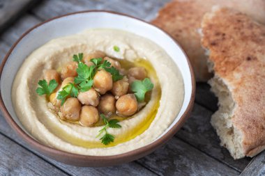 Bir tabak maydanozlu ve pide ekmekli klasik humus. Geleneksel humus salatası
