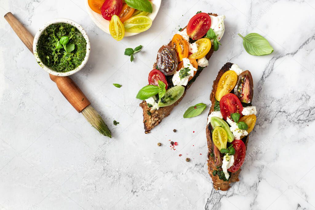 Bruschetta sandwiches with tomatoes,burrata cheese and pesto. Traditional  - grilled bruschetta toasts.