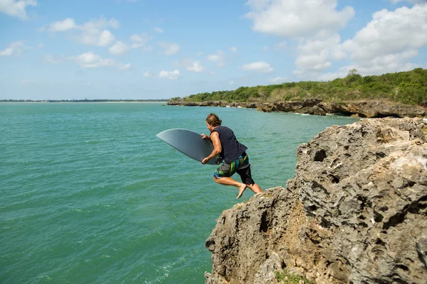 Surfer skacze z klifu do morza. Bali Indonezja — Zdjęcie stockowe