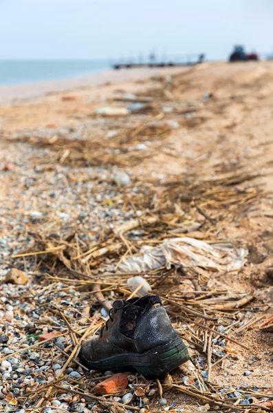 Pollution: shoes, garbages, plastic, and wastes on the beach after winter storms. Azov sea. Dolzhanskaya Spit — Stock Image Pollution: shoes, garbages, plastic, and wastes on the beach after winter storms. Azov sea. Dolzhanskaya Spit Stock Picture