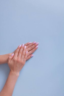 Şık moda kadın manikürü. Mavi arka planda mükemmel pembe manikürlü güzel bir kadın eli..