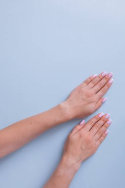Şık moda kadın manikürü. Güzel genç kadınlar ellerini mavi arka planda tutar..