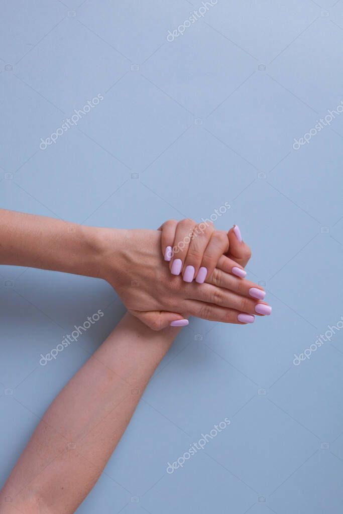 Pink manicure in beautiful style. Creative design. Two beautiful womans hands with manicure isolated on blue background.