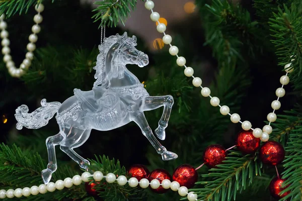 Toy horse on Christmas tree on background with lights and red and white beads — Stock Photo, Image