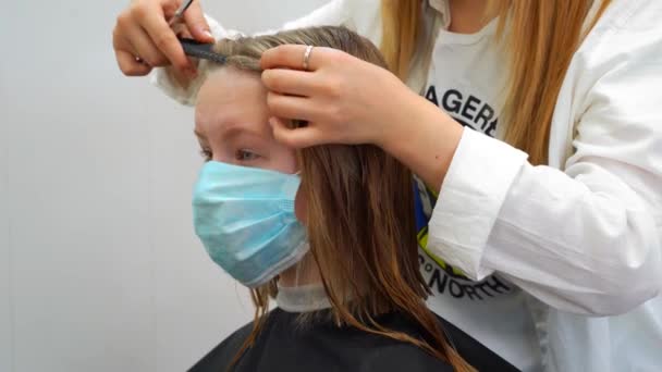 Una chica lleva máscara de la medicina con el pelo mojado consigue un corte de pelo en una barbería en el entrenamiento en línea — Vídeo de stock