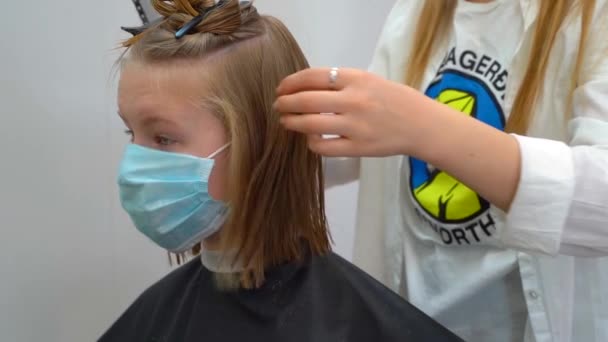 Девушка носит медицинскую маску с прической в парикмахерской — стоковое видео