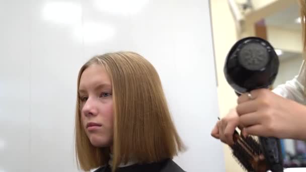 Dry and style hair of young girl with a haircut square in the barber shop — Stock Video