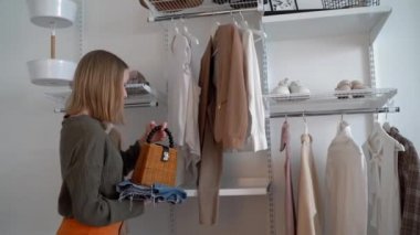 Genç, elinde bir saman çantası ve kot pantolon tutuyor ve soyunma odasının yanında duruyor. Bir ergen için moda. Giysileri ayırmak ve işleri yoluna koymak..