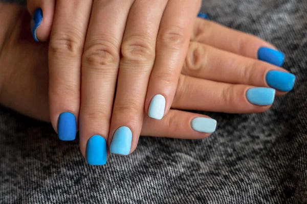 Ludzkie palce z pięknym manicure w niebieskim kolorze na tle czarnych dżinsów — Zdjęcie stockowe