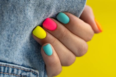 Turuncu, pembe, mavi, sarı renkli parlak tırnaklı avuç içinde siyah kot bulunur.