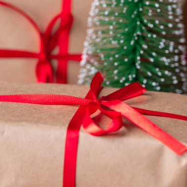 Kırmızı kurdeleli geri dönüşümlü kağıda sarılmış Noel hediyesi kutuları.
