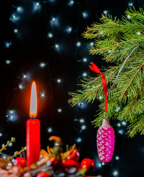 Kerst speelgoed op sparren takken en rode kaars — Stockfoto