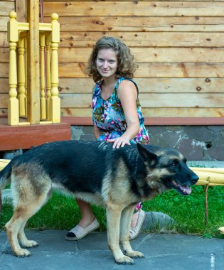 Köpeğiyle evin bahçesinde Alman çoban köpeği olan kız.