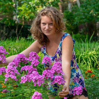 Bahçıvanlık. Çiçek tarlasında pembe fenikle ilgilenen bir kız.