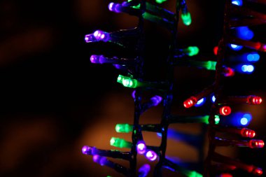 Farklı renklerde Noel ışıklandırması güç kablolarında asılı