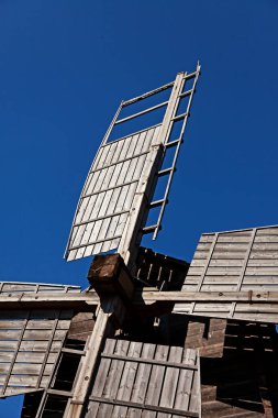 Mavi gökyüzüne karşı eski ahşap bir yel değirmeninin kanatları 