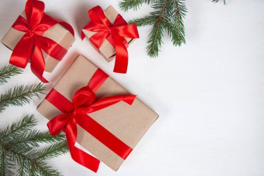 Yeni yıl kompozisyonu. Firavun dalları, hafif arka planda kırmızı fiyonklarla süslenmiş hediyelerle süslenmiş ambalajlar. Noel konsepti. Düz yerde, üst tarafta. Pankart.