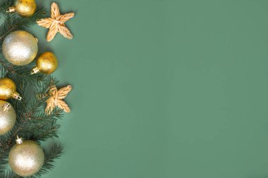 Noel kompozisyonu. Altın fiyonklu bir hediye, köknar dalı, yeşil arka planda Noel süslemeleri. Düz konum, üst görünüm, kopyalama alanı. Kış festivali konsepti.