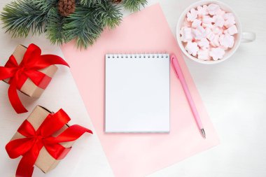 Notlar için beyaz not defteri, arka planda köknar dalı. Düz konum, üst görünüm, metin için boşluk kopyala. Noel şenlik kompozisyonu.