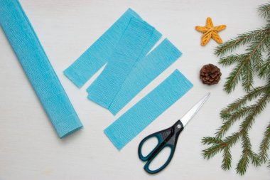 Kağıttan Noel ağacı yapmak. Masadaki makas, mavi kağıt ve köknar dalları. Orijinal bir çocuk sanat projesi. Diy konsepti. Adım adım fotoğraf talimatları. Adım 2.