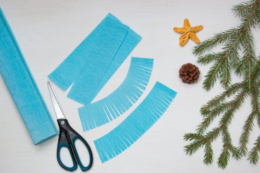 Kağıttan Noel ağacı yapmak. Masadaki makas, mavi kağıt ve köknar dalları. Orijinal bir çocuk sanat projesi. Diy konsepti. Adım adım fotoğraf talimatları. Adım 3.