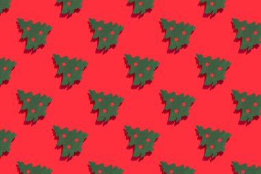 Kırmızı arka planda yeşil Noel ağaçları olan kusursuz bir düzen. Sert ışık. Yeni Yıl ve Noel kavramı.