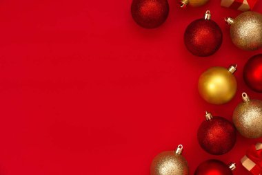 Kırmızı ve altın renkli Noel topları kırmızı arka planda fotokopi alanı ile süslenmiş. Noel kompozisyonu. Düz yerde, üst tarafta. Asgari biçim.