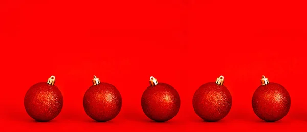 Red shiny Christmas balls on a red background. New year and christmas concept. Minimal festive composition. copy space for text.