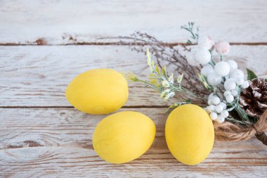 Paskalya kartı. Ahşap beyaz bir masada pastel sarı yumurtalar. Metin için alanı kopyala.