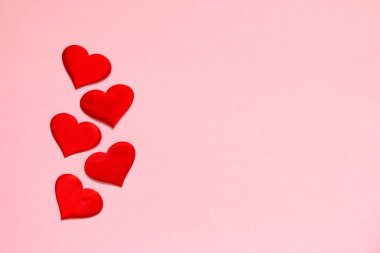 Pembe arka planda kırmızı kalpler olan tebrik kartı. Sevgililer Günü tatili konsepti. Düz yat, boşluğu kopyala.