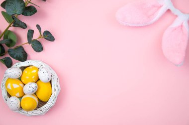 Mutlu Paskalyalar. Sarı yumurtalar ve pembe pastel arka planda bir okaliptüs dalı. Düz konum, üst görünüm, kopyalama alanı.